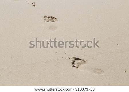 Footprints in wet sand beach