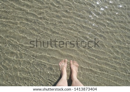 Foots in the clear water on the beach
