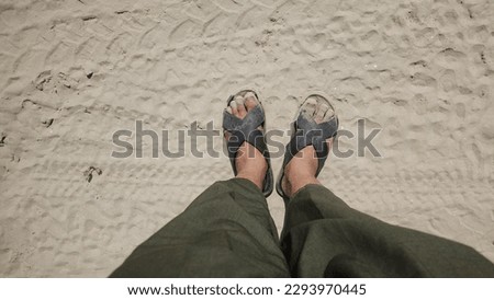 foots on  beach, wearing black sandals
