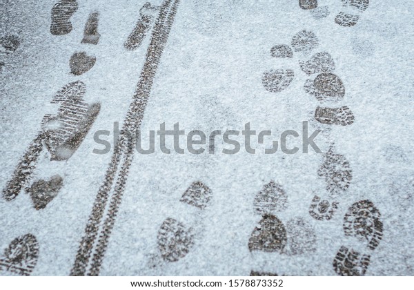 Footsteps\
and tire marks in the snow, witner background\
