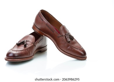 Footwear Concepts. Pair of Traditional Formal Stylish Brown Pebble Grain Tassel Loafer Shoes On White Reflective Surface. Horizontal image Composition