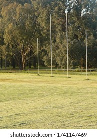 Footy Goal And Point Posts On Oval Field With Gumtree Background. 