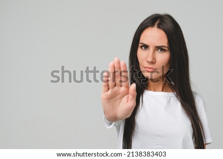 Forbidden prohibited serious caucasian young woman girl showing with palm hand stop sign gesture isolated in grey background. No pass