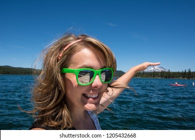 Forced Perspective Of A Female Holding Her Hand Appears To Be Touching Mt. Bachelor In The Distance From Lava Lake Along The Cascade Lakes Scenic Byway. Girl Is Smiling