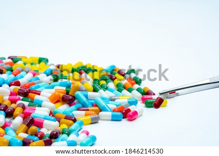 Forceps pick red-white capsule from group of capsule pills. Drugs choose. Drug selection. QA and QC in pharmaceutical factory concept. Drugs of choice. Capsule pill in laboratory for quality test.