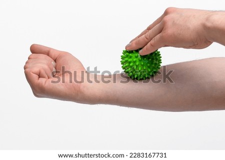 Forearm massage with a green small ball with spikes