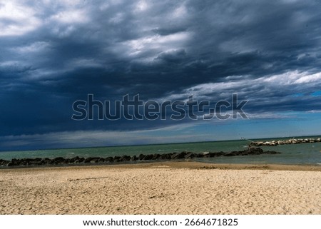 A foreboding sky looms over a serene beach, the calm sand a contrast to the ominous clouds gathering overhead. Nature's duality.