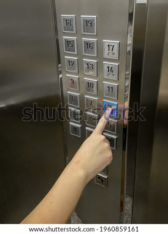 Forefinger pressing the eighth floor button in the elevator Close up businessman pressing first floor control panel button in elevator hands touching panel surface modern metal gray blue light