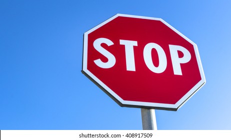 Forefront of a stop sign with a clear blue sky