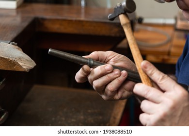 foreground, hammer hammering a silver ring to shape it in a jewelry workshop.