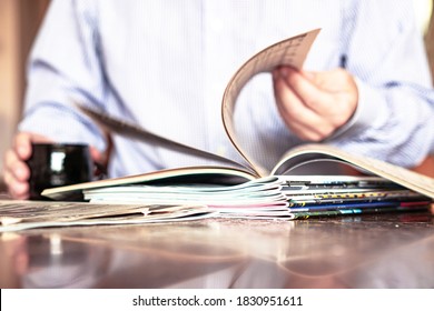In the foreground are magazines, In the background in defocus laundry reads a magazine