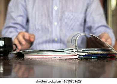In the foreground are magazines, In the background in defocus laundry reads a magazine