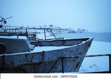 In the foreground out of focus the cape of an abandoned rusty ship. In the background is a fishing village on the shore of Lake Baikal.