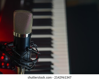 In The Foreground Is A Professional Studio Microphone And Midi Keyboard. Minimalism. Recording Studio, Vocal, Rehearsal, Rock Band, Concert, Night Club. Close-up.