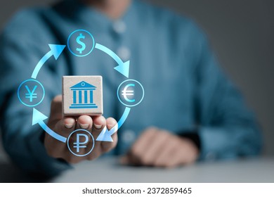 Foreign currency exchange digital concept. Businessman holds wooden cube with currency symbols of dollar, euro, ruble and yen. International money transfer or payments via online banking by fintech.