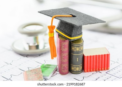 Foreign Medical School Study, Healthcare Concept : Black Graduation Cap On Books And A Heart Pulse Or Heartbeat Diagram With A Stethoscope. Medical Studies Test Out New Medicines, Surgery, Or Devices.