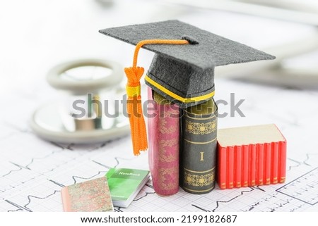 Foreign medical school study, healthcare concept : Black graduation cap on books and a heart pulse or heartbeat diagram with a stethoscope. Medical studies test out new medicines, surgery, or devices.