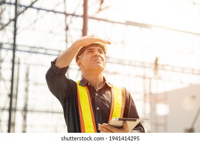 Foreman builder engineer worker looking at large building construction site sunny day hard work.