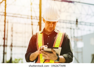 Foreman Builder Engineer Worker Using Tablet Computer To Check Building Floor Plan At Construction Site.