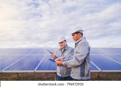 Foreman Business Checking Solar Panel At Solar Plant Field With His Worker