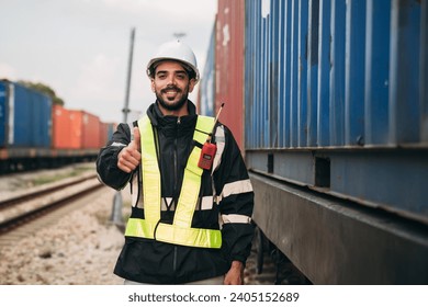 Foreman checking inventory or task details on freight train cars and shipping containers. Logistics concept, import, and export industries.