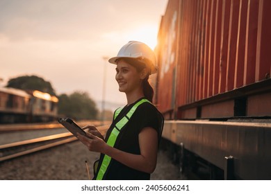 Foreman checking inventory or task details on freight train cars and shipping containers. Logistics concept, import, and export industries.