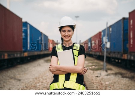 Foreman checking inventory or task details on freight train cars and shipping containers. Logistics concept, import, and export industries.