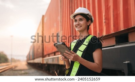 Foreman checking inventory or task details on freight train cars and shipping containers. Logistics concept, import, and export industries.