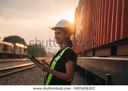 Foreman checking inventory or task details on freight train cars and shipping containers. Logistics concept, import, and export industries.