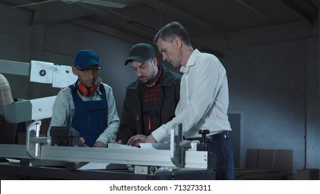 Foreman Coming To Two Workers And Explaining The Blueprints In Furniture Factory Room.