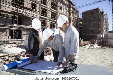 Foreman and co-workers looking at blueprints on construction site - Powered by Shutterstock