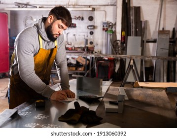 Foreman measures part and takes notes on paper. High quality photo