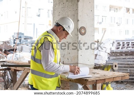 Foreman officer inspector, building Inspector, engineer or inspector at construction site checking and inspecting progressing work in construction site or building, in hardhat and high-visibility vest