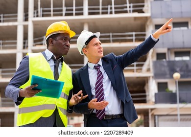 Foreman Showing Builder Something At The Construction Site By Pointing His Hand