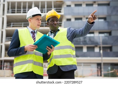 Foreman Showing Builder Something At The Construction Site By Pointing His Hand