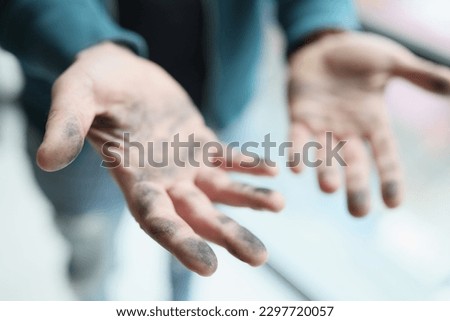 Foreman shows dirty palms after cleaning dusty premise before doing renovation in apartment. Man demonstrates hands with grime at sunlight