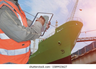 Foreman With Tablet IPad Inspection Damage In Floating Dock, Ship Moored In Dock Yard During Maintenance In Shipyard.