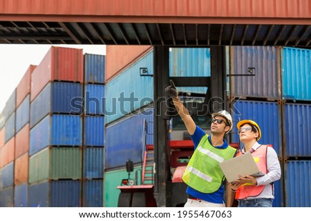  Foreman using laptop computer in the port of loading goods. Foreman control loading containers boxs from cargo freight ship for import export.