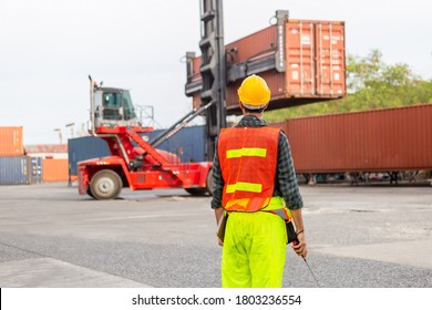 Foreman Worker In Hardhat And Safety Vest Holding Clipboard Checklist And Two-way Radio Control Loading Containers Box From Cargo