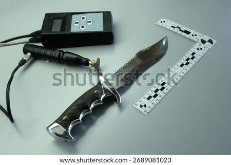 Forensic analysis of bladed weapons, measuring the hardness of a knife blade using an ultrasonic device. Evidence examination in a police forensic laboratory.
