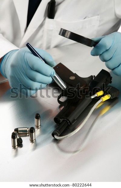 forensic analysis - a forensics\
lab technician examines a hand gun for finger prints, blood\
splatter, and any other residue or evidence to be used in a court\
case
