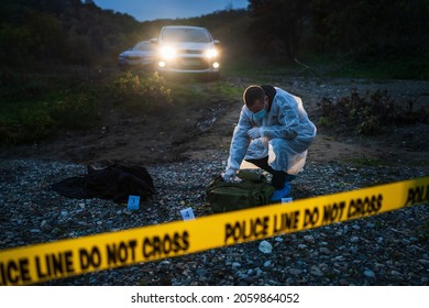 Forensic police investigator collecting evidence at the crime scene in nature at night