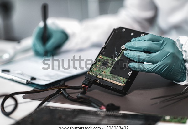 Forensic Science Investigator\
Examining Computer Hard Drive. Digital Forensic Science\
Concept.