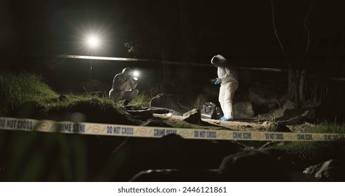 Forensic team, photographer and crime scene at night for investigation or observation with hazmat or police tape. Collaboration, expert investigator or outdoor in forest for evidence or case research - Powered by Shutterstock