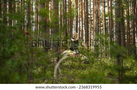 Forest baths, restoring health and strength on the weekend, adult woman sitting on a rock ledge