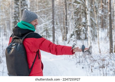 in the forest, the bird takes the seeds from his hand. feeding birds in winter. nuthatch, chickadee, titmouse - Powered by Shutterstock