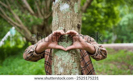 Forest conservationist forms heart shape with their hands around a tree trunk in a peaceful park. love for nature, commitment to environmental protection, importance of sustainable ecosystems.