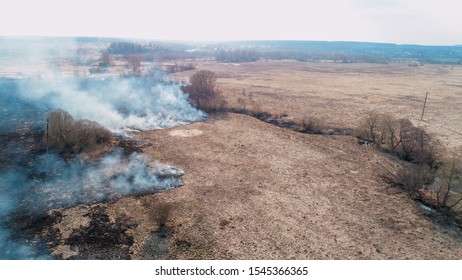 Forest And Field Fire. Dry Grass Burns, Natural Disaster. Aerial View. Extensive Burning Of Grass And Shrubs, All Around Is Obscured By Haze.