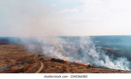 Forest And Field Fire. Dry Grass Burns, Natural Disaster. Aerial View. Extensive Burning Of Grass And Shrubs, All Around Is Obscured By Haze.