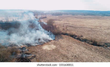 Forest And Field Fire. Dry Grass Burns, Natural Disaster. Aerial View. Extensive Burning Of Grass And Shrubs, All Around Is Obscured By Haze.